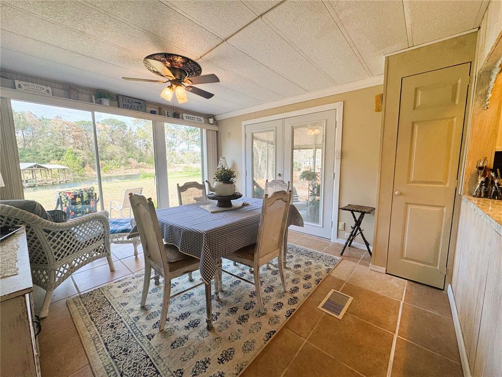A dining area with a table, chairs, tile floors, and large windows overlooking a lake — 107 ROYAL PALM DRIVE, LEESBURG, FL