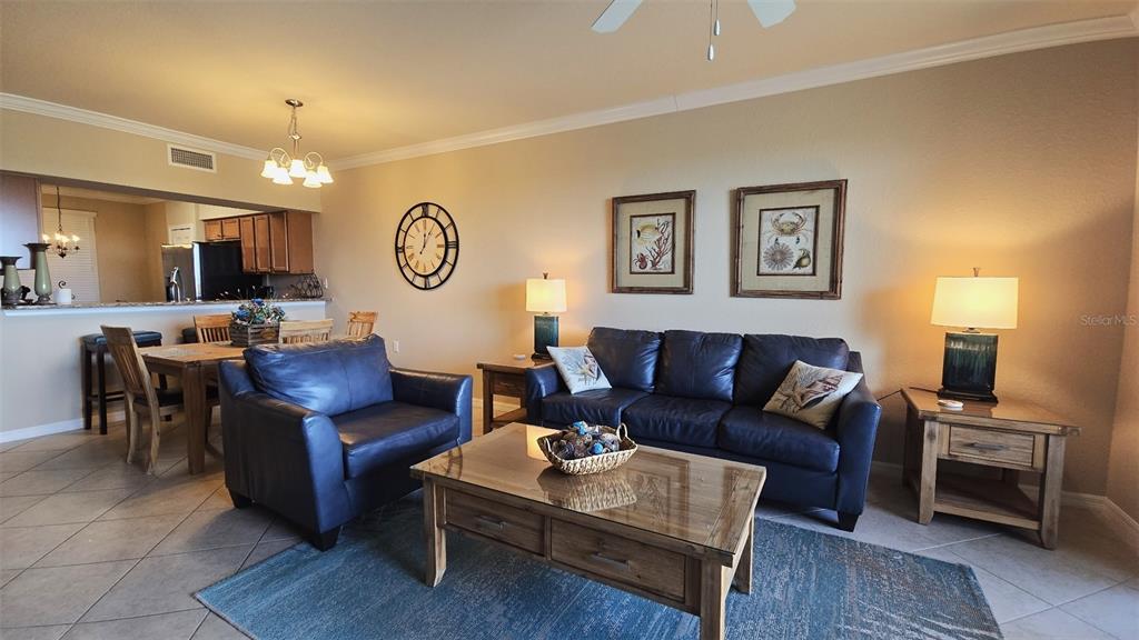 A living room with a blue leather sofa and armchair, wooden coffee table, and dining area — 7005 RIVER HAMMOCK DRIVE UNIT 305, BRADENTON, FL