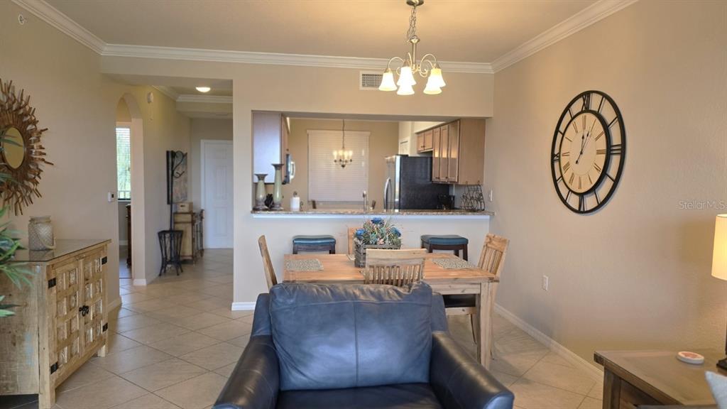 A dining area and kitchen with a breakfast bar, tile flooring, and a large wall clock — 7005 RIVER HAMMOCK DRIVE UNIT 305, BRADENTON, FL