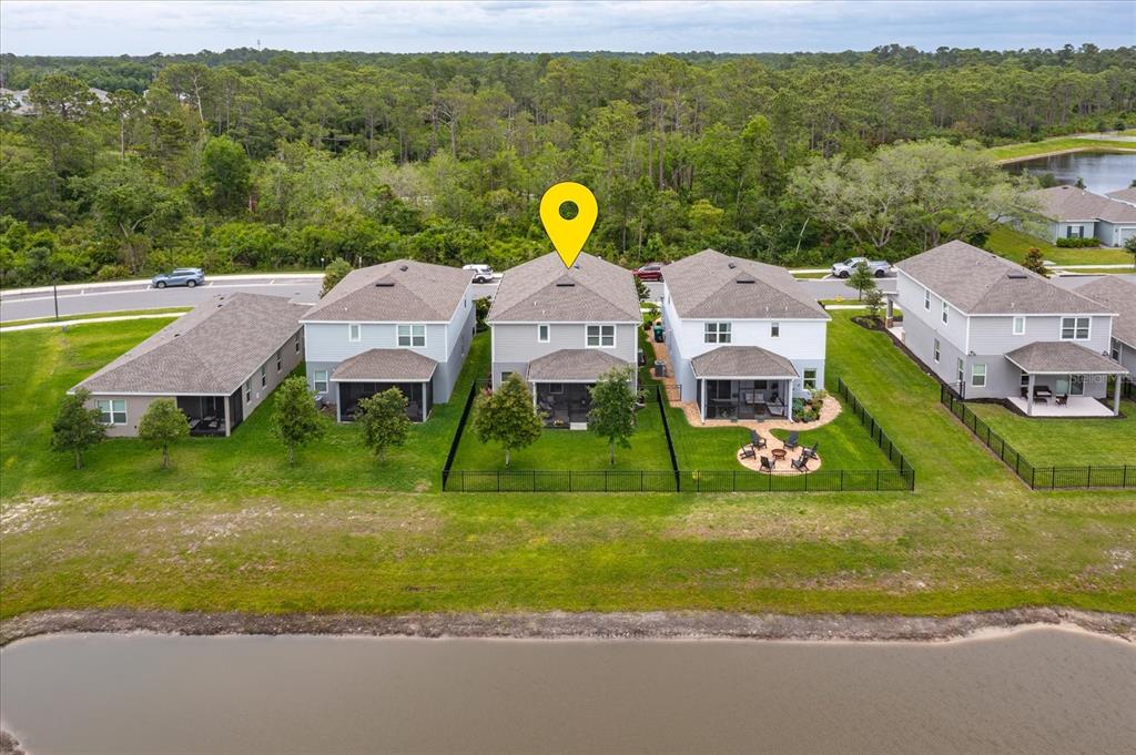 An aerial view shows a row of suburban houses with fenced backyards facing a pond — 7016 LANIER FALLS ROAD, DELAND, FL