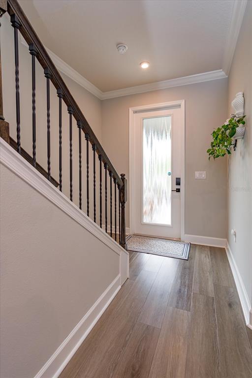 An entryway features wood-look flooring, a staircase with dark metal balusters, and a glass-paneled door — 7016 LANIER FALLS ROAD, DELAND, FL