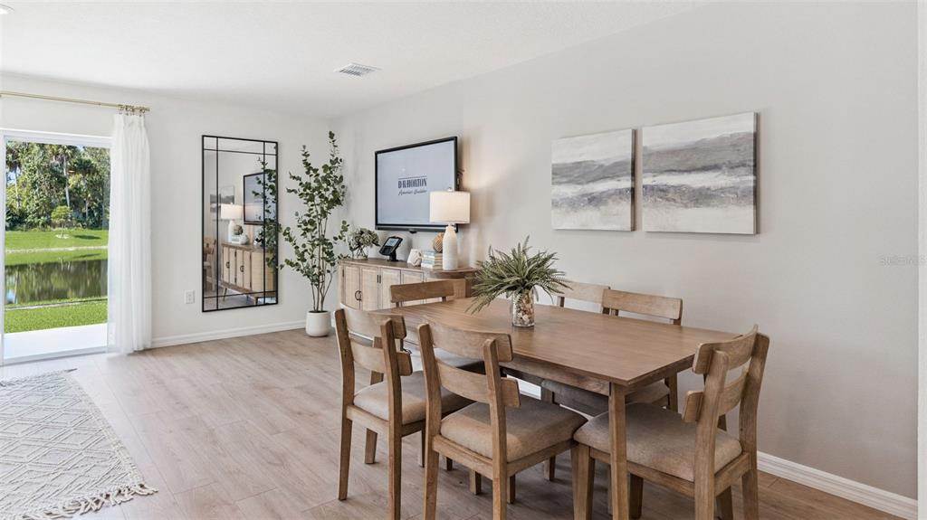 A dining room with a wooden table, chairs, a sideboard, and a view of water — 515 PROSECCO DRIVE, HOLLY HILL, FL
