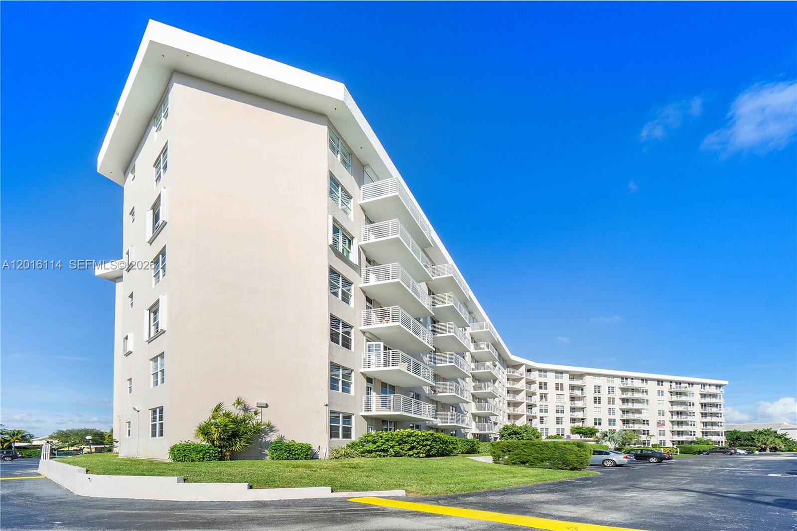 A multi-story residential building with balconies stands above a parking lot under a blue sky — 2851 S Ocean Blvd # 7U, Boca Raton FL 33432, BOCA RATON, FL