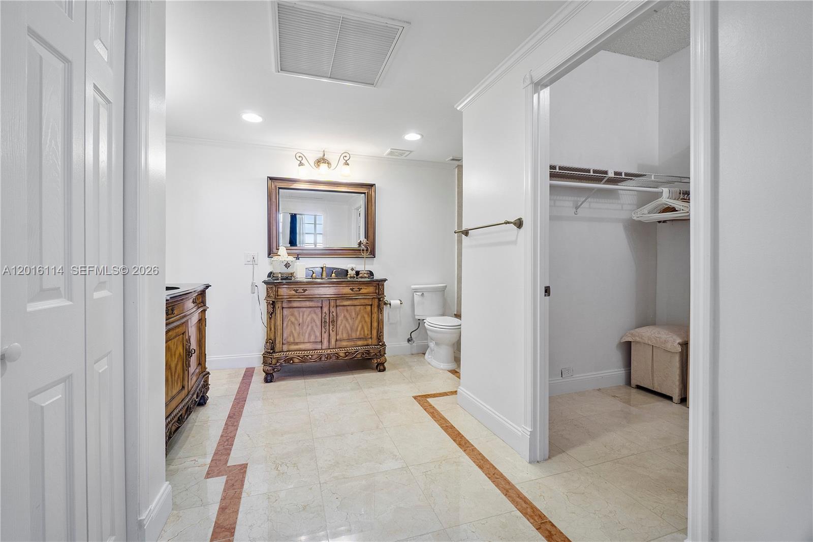 A bathroom features a wooden vanity, a toilet, and an adjacent walk-in closet — 2851 S Ocean Blvd # 7U, Boca Raton FL 33432, BOCA RATON, FL