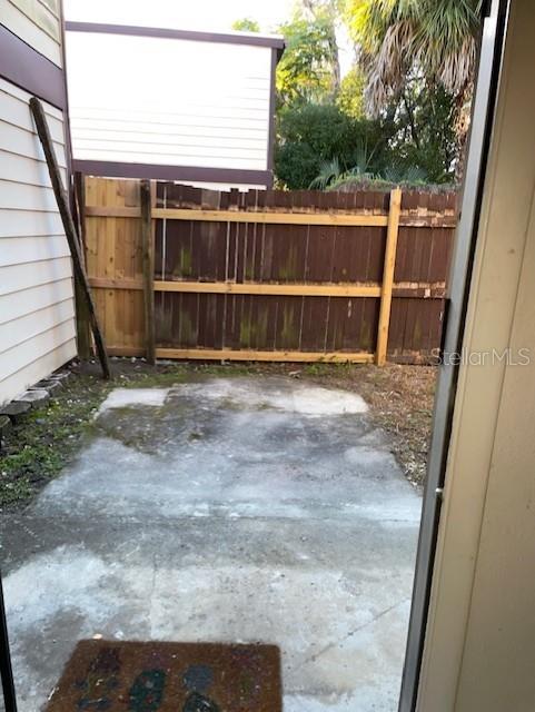 A concrete patio sits outside a sliding glass door next to a wooden privacy fence — 3994 CRAYRICH CIRCLE UNIT C4, ORLANDO, FL