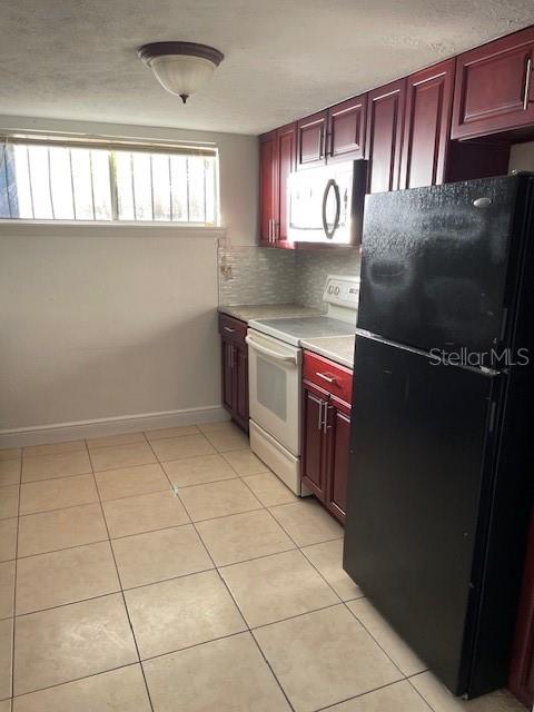 A kitchen features cherry-toned cabinets, a black refrigerator, a white stove, and tiled flooring — 3994 CRAYRICH CIRCLE UNIT C4, ORLANDO, FL