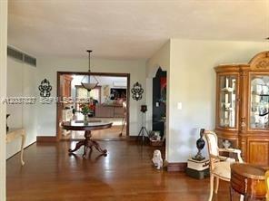 A dining room with hardwood floors, a round wooden table, and a large display cabinet — HOMESTEAD, FL