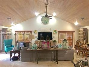 A living room features a vaulted wood-paneled ceiling, a ceiling fan, and a large television — HOMESTEAD, FL