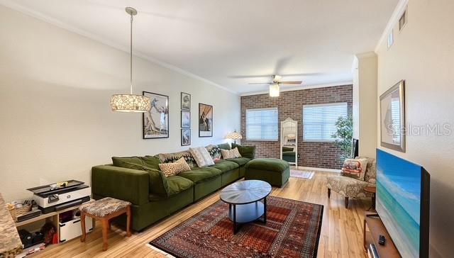 A living room features a green sectional sofa, a brick accent wall, and a patterned rug — 1064 N TAMIAMI TRAIL UNIT 1524, SARASOTA, FL