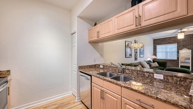 A kitchen features light wood cabinets, granite countertops, a stainless steel dishwasher, and a pass-through window — 1064 N TAMIAMI TRAIL UNIT 1524, SARASOTA, FL