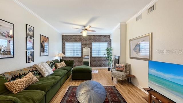 A living room features a green sectional sofa, a brick accent wall, and a television — 1064 N TAMIAMI TRAIL UNIT 1524, SARASOTA, FL