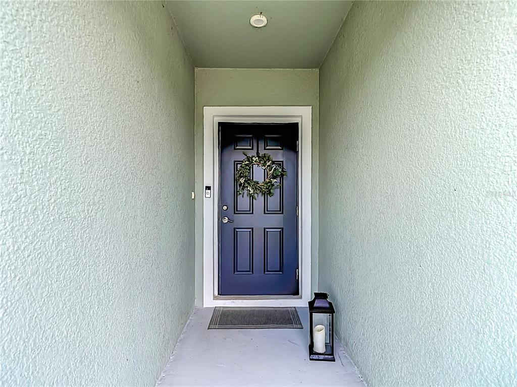 A dark blue front door with a wreath sits in a light green entryway — 14409 WHITEWATER WAY, BROOKSVILLE, FL