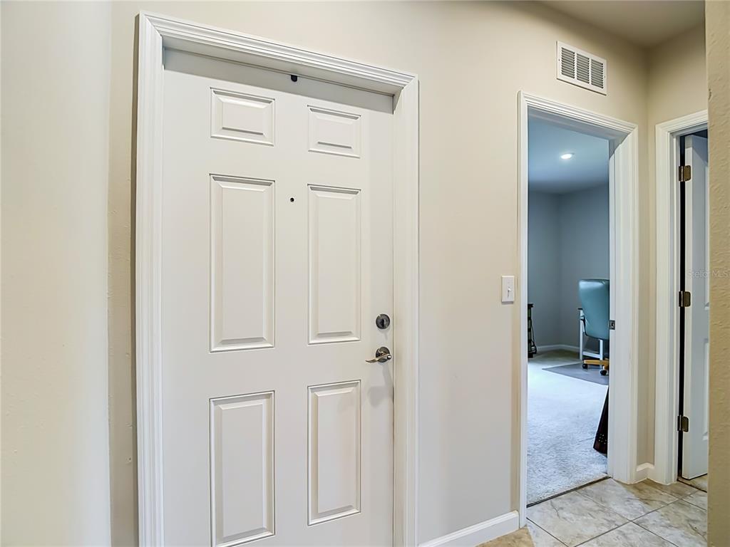 A white six-panel door stands next to an open doorway leading into a carpeted room — 14409 WHITEWATER WAY, BROOKSVILLE, FL