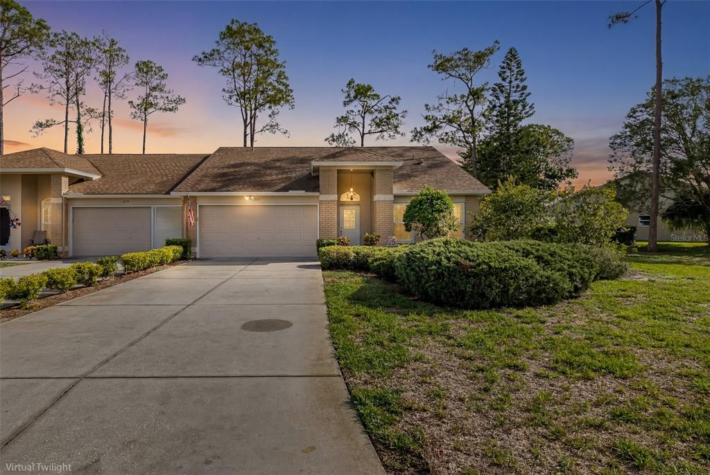 A single-story attached house with a two-car garage and a concrete driveway at twilight — 9519 SCENIC PINE COURT, NEW PORT RICHEY, FL