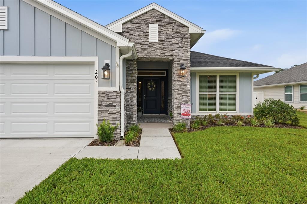 A single-story house features a stone facade, blue vertical siding, and a white garage door — 203 SW SILVER PALM DRIVE, LAKE CITY, FL