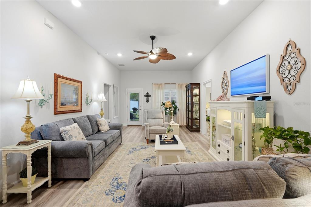 A living room features a gray sofa, a white media console, and a ceiling fan — 203 SW SILVER PALM DRIVE, LAKE CITY, FL