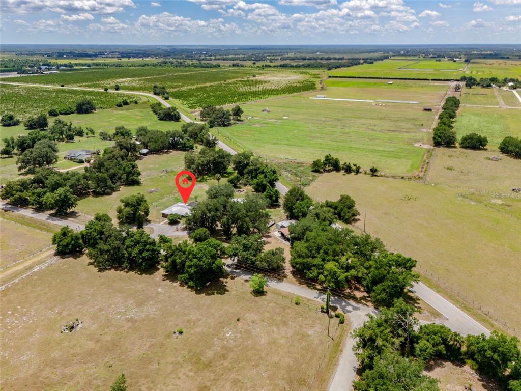 An aerial view shows a house surrounded by trees and large, open grassy fields — 2087 SW GARNER AVENUE, ARCADIA, FL