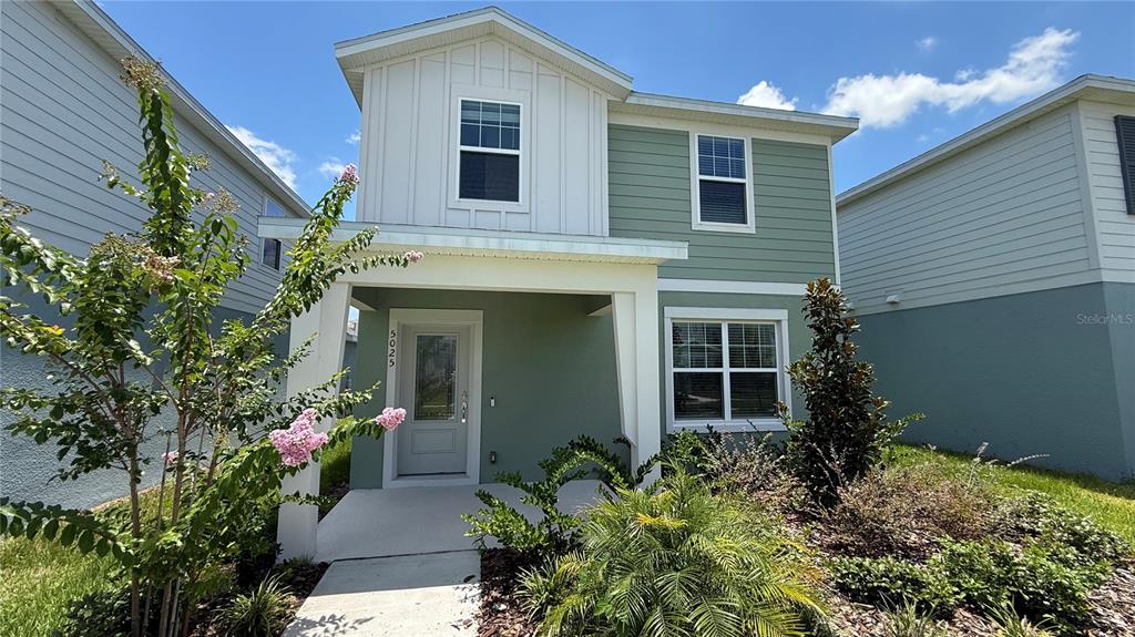 A two-story house with green and white siding, a covered porch, and a front yard — 5025 FURROWED WAY, ST CLOUD, FL