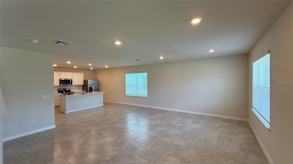 An open-concept living area features light tile flooring, recessed lighting, and an adjacent kitchen — 5025 FURROWED WAY, ST CLOUD, FL