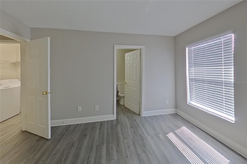 An empty living room features gray wood-look flooring, a ceiling fan, and white French doors — 162 HIDDEN POINTE LANE, GROVELAND, FL