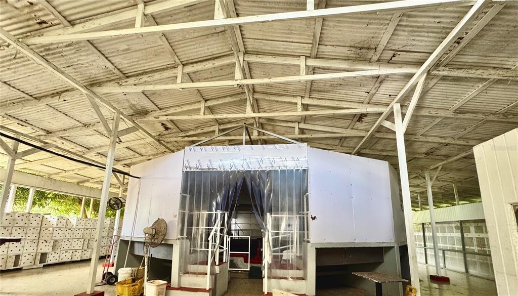 An open-air structure features a central enclosed room with plastic curtains under a metal roof — Barrio Quebrada Yeguas LA PLENA 94, SALINAS, PR