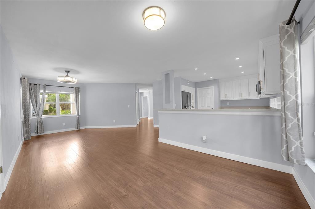A spacious living room features vaulted ceilings, wood-look flooring, a piano, and sliding glass doors — 15876 SANCTUARY DRIVE, TAMPA, FL