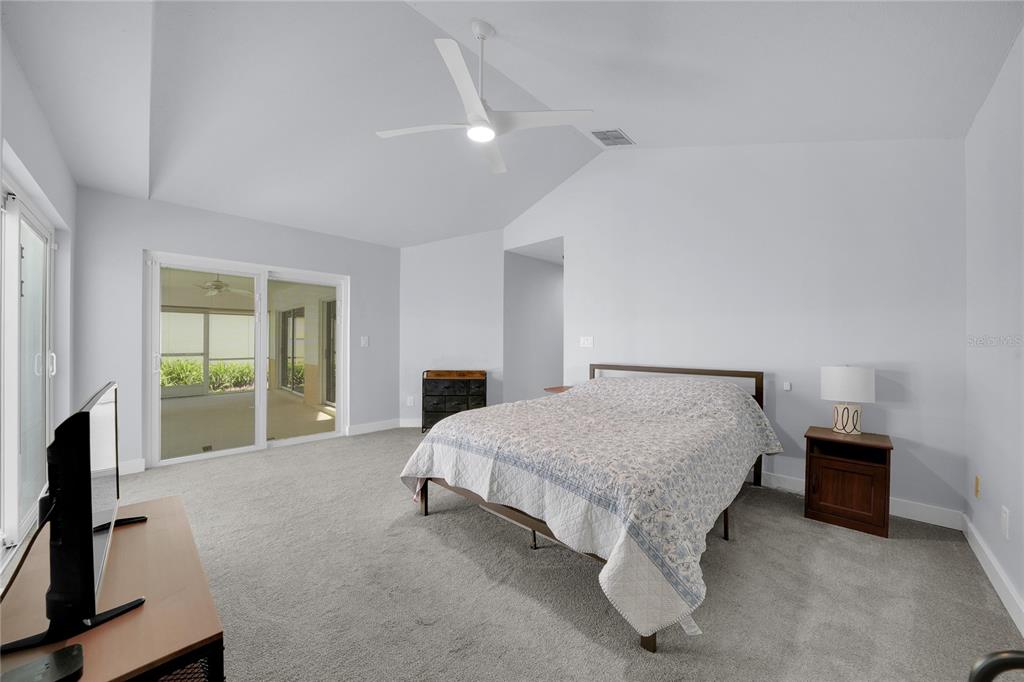 An open-concept living room with light gray walls, wood-look flooring, and a kitchen breakfast bar — 15876 SANCTUARY DRIVE, TAMPA, FL