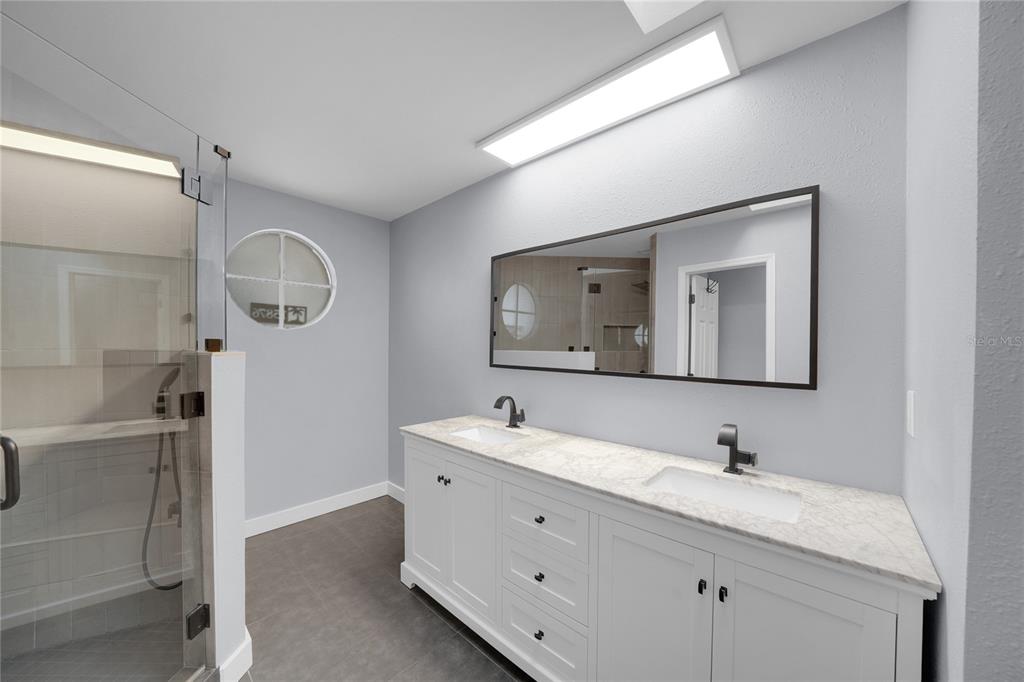 A kitchen features white cabinets, stainless steel appliances, a glass block backsplash, and wood flooring — 15876 SANCTUARY DRIVE, TAMPA, FL