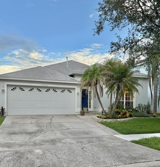 A single-story house with a two-car garage, light-colored siding, and palm trees in the yard — 13620 WATERHOUSE WAY, ORLANDO, FL