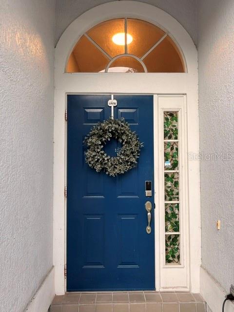 A blue front door with a wreath and a sidelight window under an arched transom — 13620 WATERHOUSE WAY, ORLANDO, FL