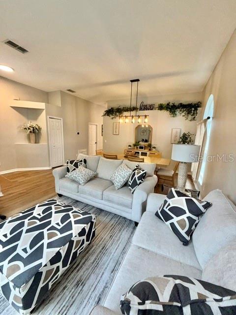 A living room features a light-colored sofa, a patterned ottoman, and a dining area beyond — 13620 WATERHOUSE WAY, ORLANDO, FL