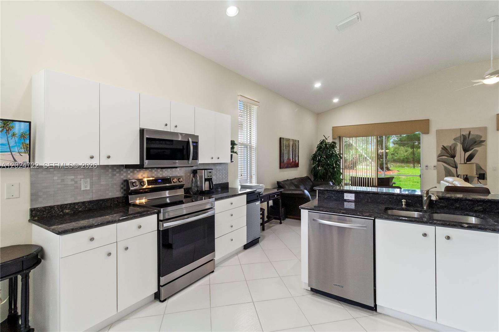 A kitchen features white cabinets, dark granite countertops, stainless steel appliances, and tile flooring — 10776 Grande Palladium Way, Boynton Beach FL 33436, BOYNTON BEACH, FL