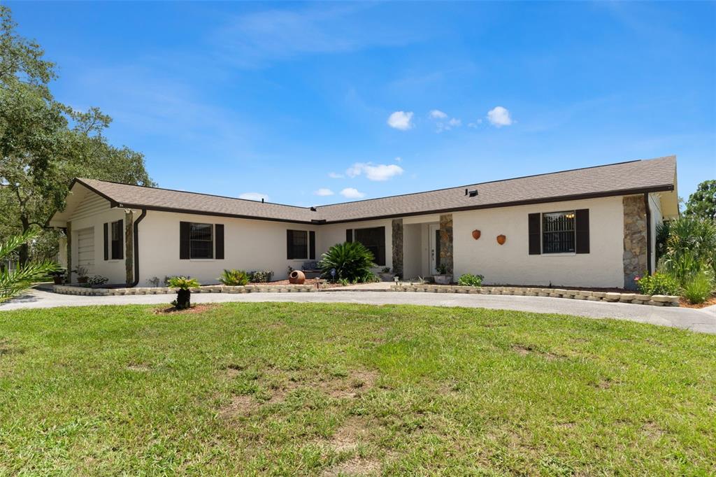A single-story house with a white stucco exterior, dark shutters, and a stone-accented entryway — 13260 TAYLOR STREET, BROOKSVILLE, FL
