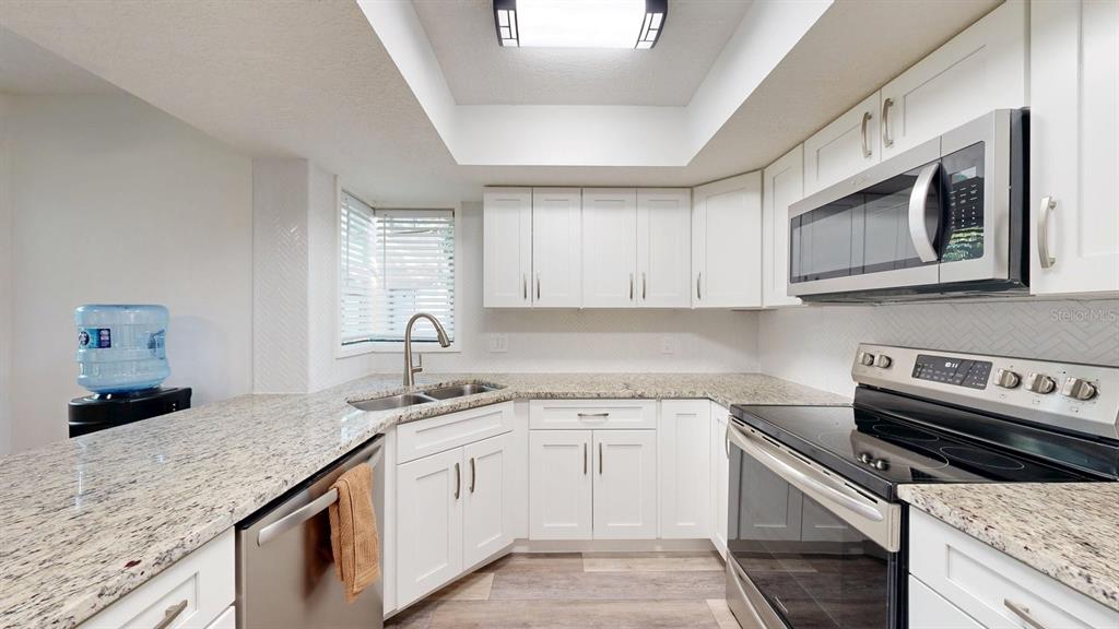 A kitchen features white cabinets, granite countertops, stainless steel appliances, and a recessed ceiling light — 15 PINE HURST PLACE UNIT 15, PALM COAST, FL