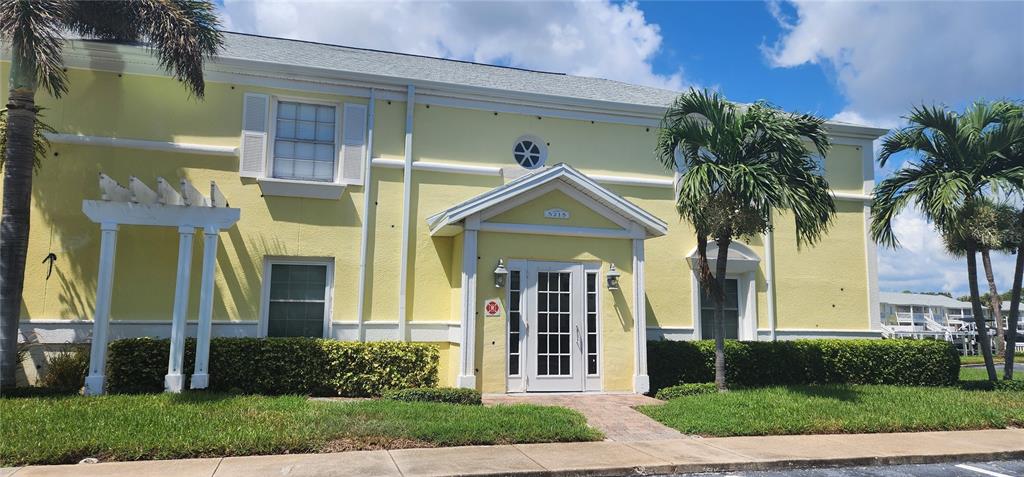 A two-story yellow building with a white front entrance, pergola, and palm trees — 5215 COQUINA KEY DRIVE SE UNIT B, ST PETERSBURG, FL
