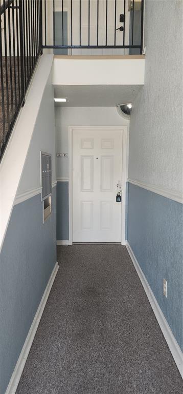A hallway with gray carpet, blue wainscoting, a white door, and a black metal staircase — 5215 COQUINA KEY DRIVE SE UNIT B, ST PETERSBURG, FL