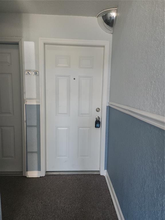 A white door with a lockbox sits in a hallway with blue and white walls — 5215 COQUINA KEY DRIVE SE UNIT B, ST PETERSBURG, FL