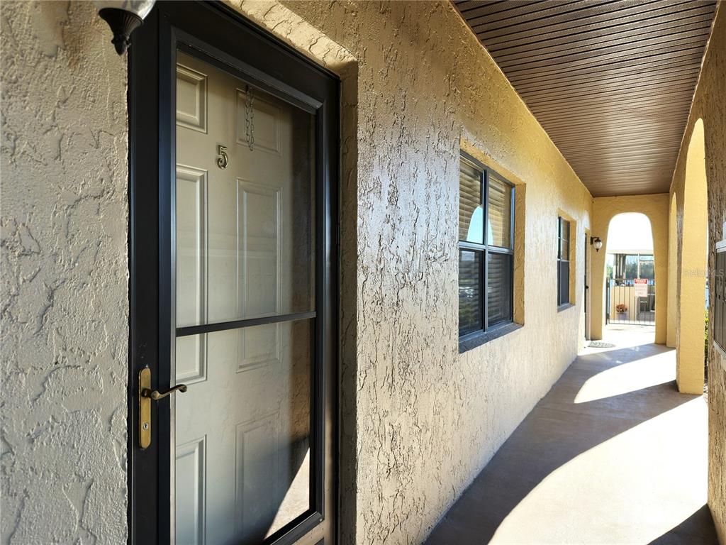 A covered exterior walkway leads to a front door marked with the number five — 1217 AQUI ESTA DRIVE UNIT 5, PUNTA GORDA, FL