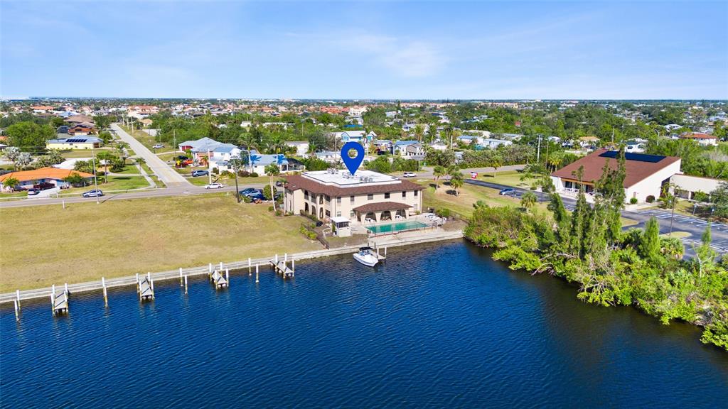 An aerial view shows a multi-story building with a pool and dock on a canal — 1217 AQUI ESTA DRIVE UNIT 5, PUNTA GORDA, FL