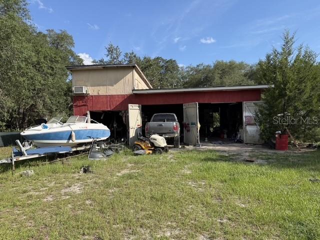 A boat on a trailer sits in front of a red garage with an open bay — 101 ALLEN DRIVE, PALATKA, FL