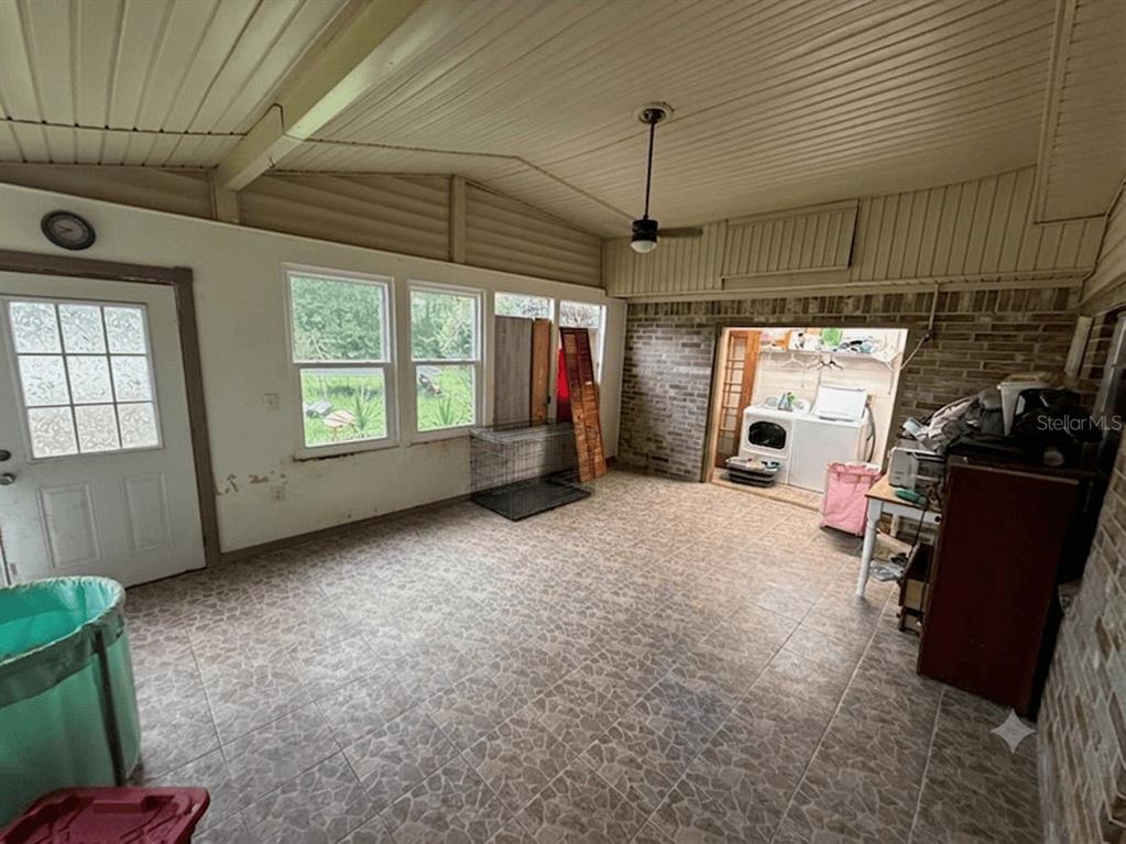 A sunroom with tiled floors, a ceiling fan, and an open laundry area with appliances — 101 ALLEN DRIVE, PALATKA, FL