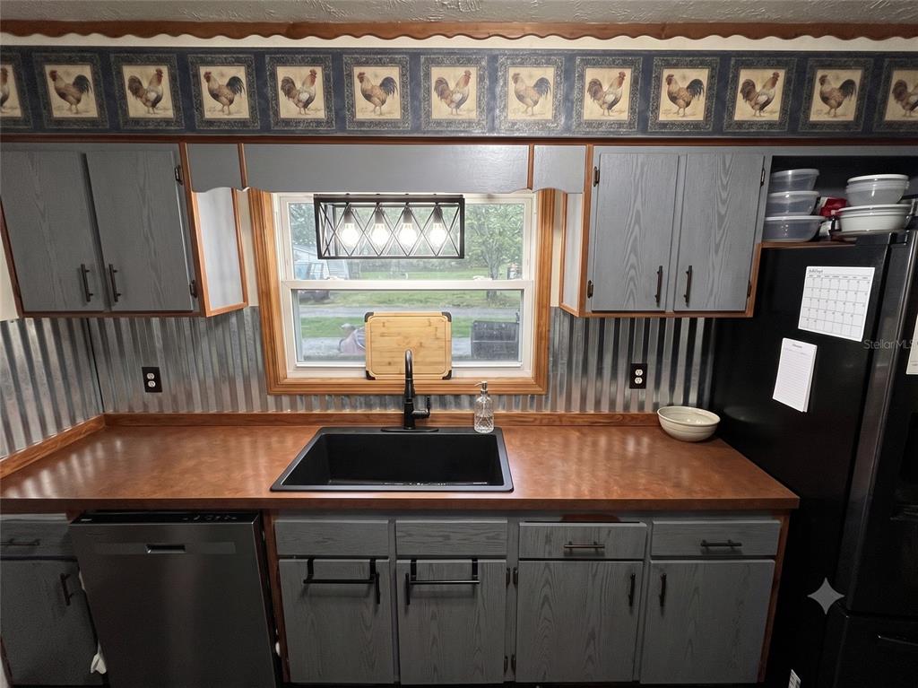 A kitchen features gray cabinets, a corrugated metal backsplash, and a black sink — 101 ALLEN DRIVE, PALATKA, FL