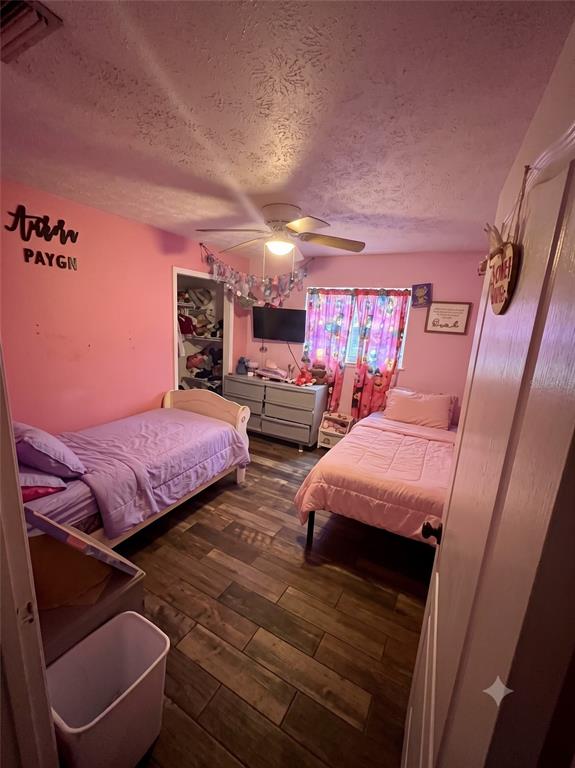 A bedroom with two twin beds, pink walls, wood-look tile flooring, and a ceiling fan — 101 ALLEN DRIVE, PALATKA, FL