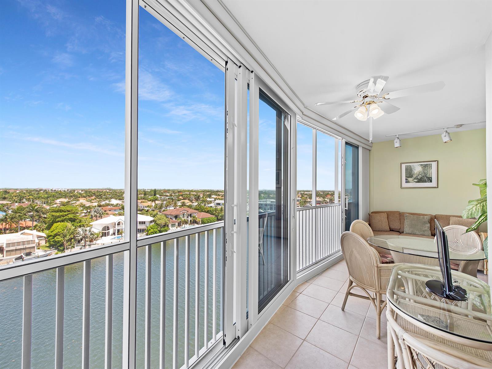 A sunroom with tile floors, wicker furniture, and large windows overlooking a waterfront neighborhood — 3310 S Ocean Boulevard # 928d, Highland Beach FL 33487, HIGHLAND BEACH, FL