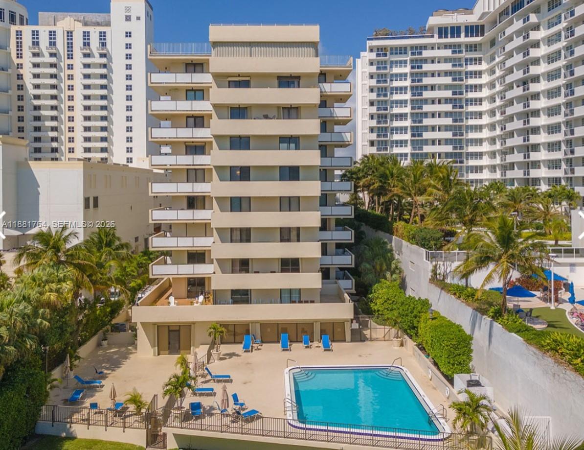 An exterior view of a multi-story apartment building with a swimming pool and lounge chairs — 1621 Collins Ave # 701, Miami Beach FL 33139, MIAMI BEACH, FL