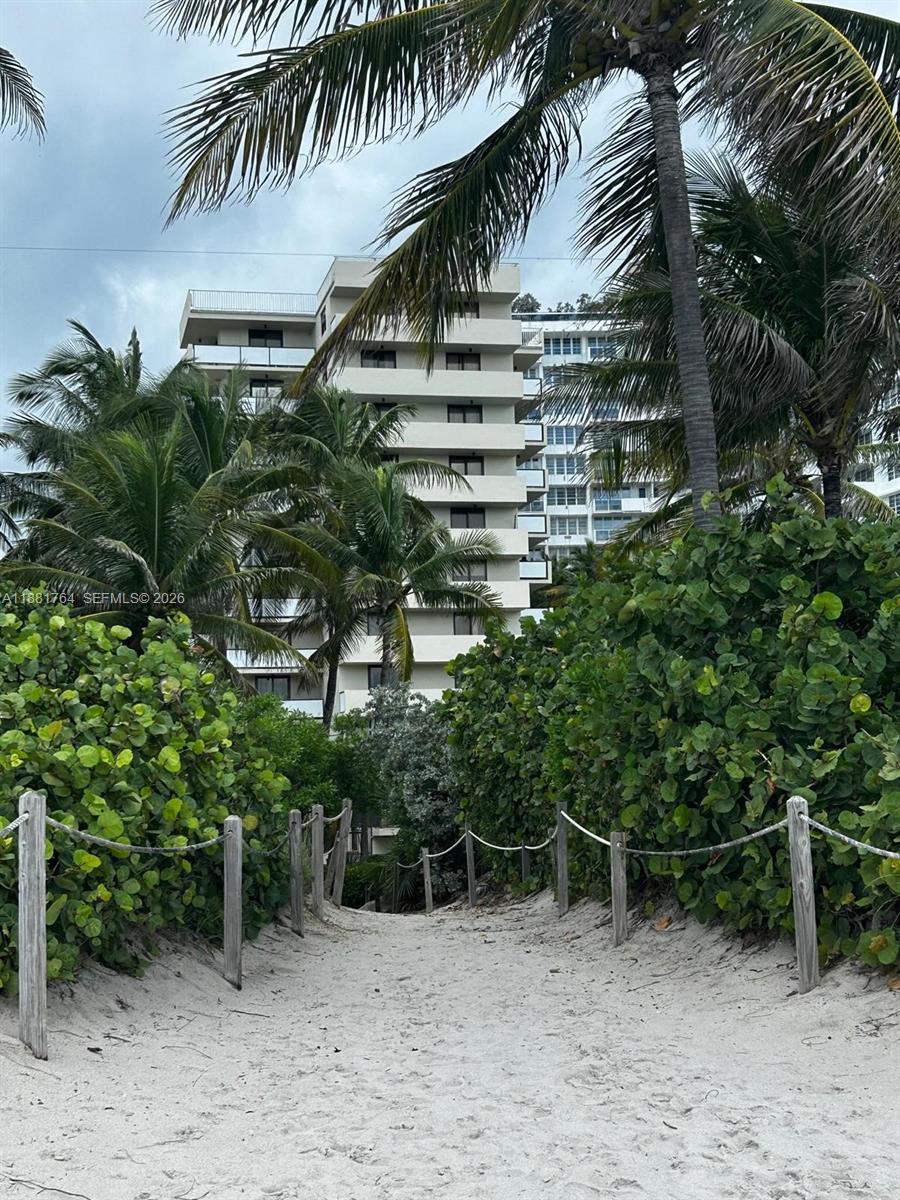 A sandy path leads through tropical foliage toward a multi-story residential building — 1621 Collins Ave # 701, Miami Beach FL 33139, MIAMI BEACH, FL