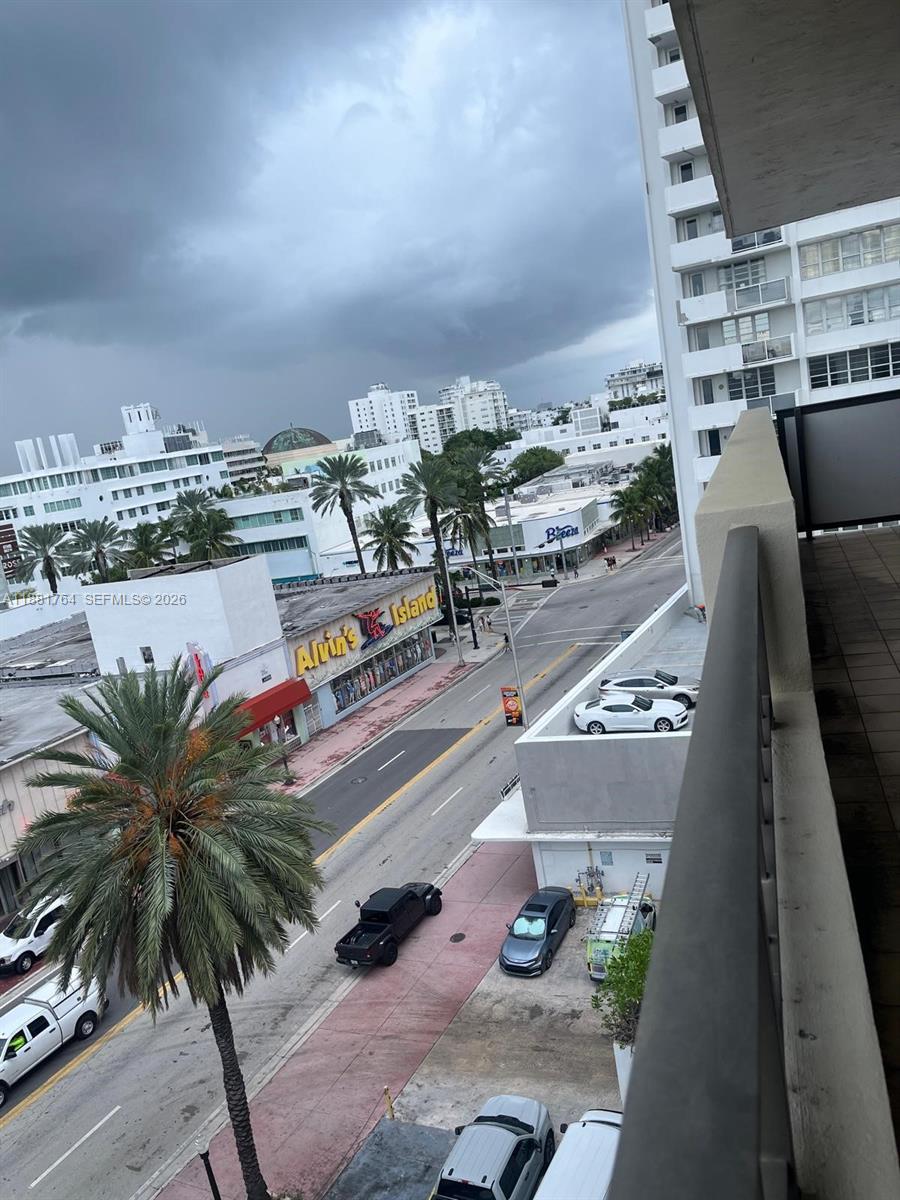 An elevated view from a balcony overlooks a city street with palm trees and buildings — 1621 Collins Ave # 701, Miami Beach FL 33139, MIAMI BEACH, FL