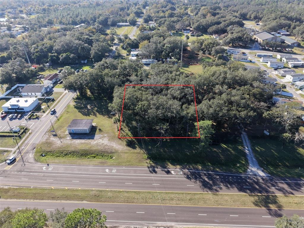 An aerial view shows a wooded, rectangular lot outlined in red next to a road — 15192 E COLONIAL DR, ORLANDO, FL