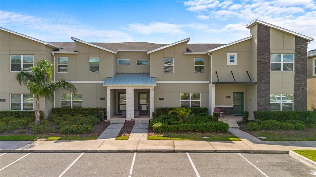 A multi-unit residential building with tan stucco siding, stone accents, and a parking lot — 2957 PENELOPE LOOP, KISSIMMEE, FL
