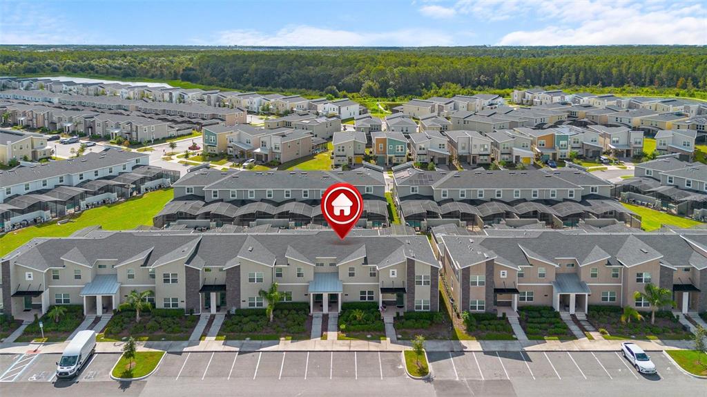 An aerial view shows a row of modern townhouses with parking spaces in the foreground — 2957 PENELOPE LOOP, KISSIMMEE, FL